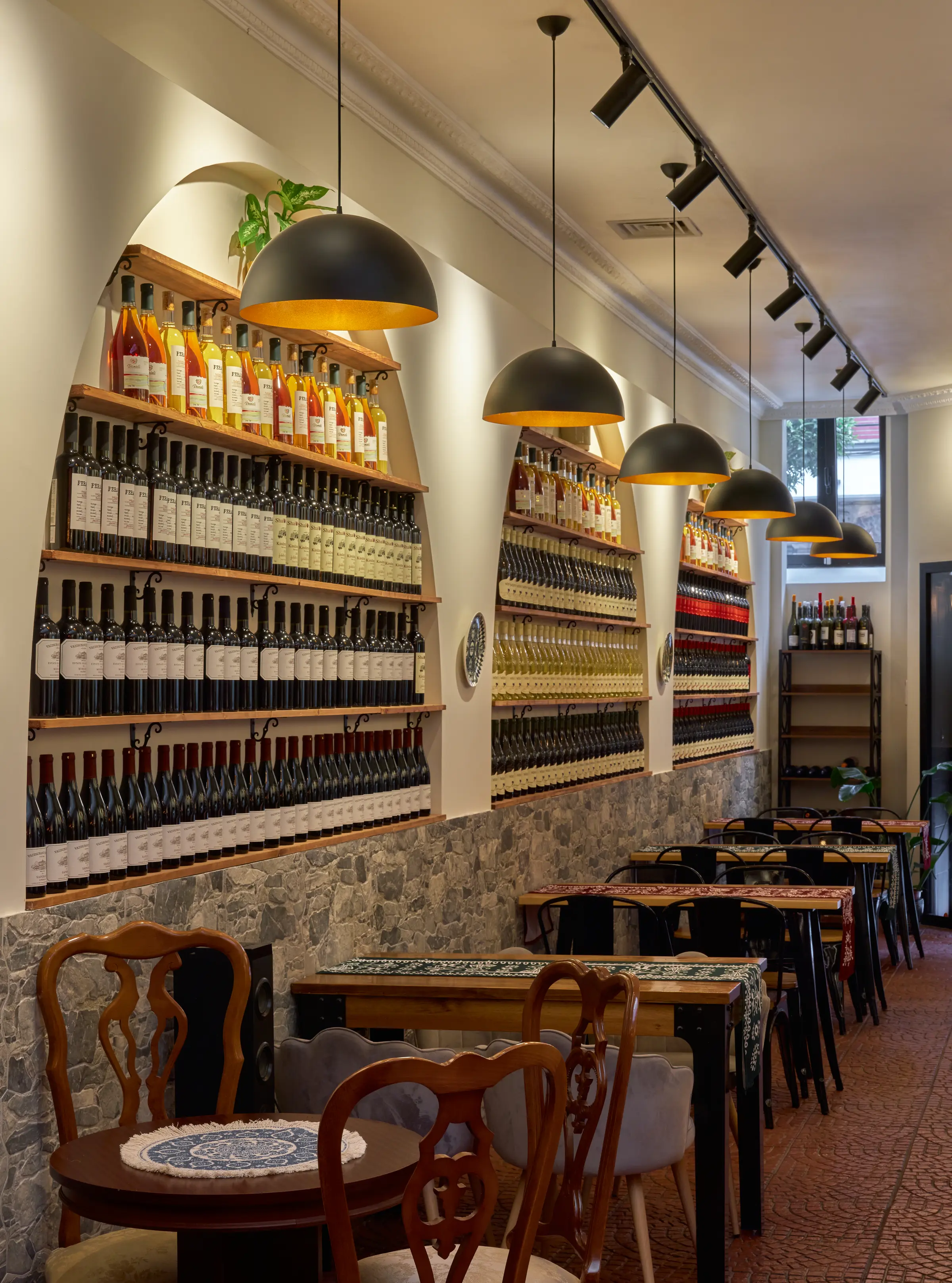 Arcos de la bodega vistos en diagonal, con mesas vestidas y lámparas colgantes en primer plano